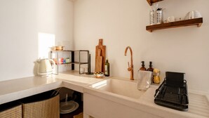 A kitchen with a white countertop, a sink, a wooden shelf with kitchenware, and a black dish rack. - Casa Adamare - Charming Luxury Stay (Ostuni)