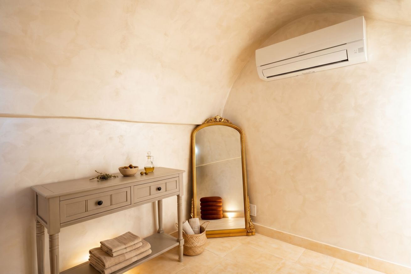 A bathroom with a vanity, a mirror, a towel rack, and an air conditioning unit.
