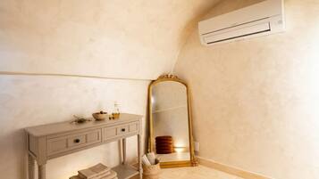 Un bagno con un mobile lavabo, uno specchio, un portasciugamani e un condizionatore d'aria.