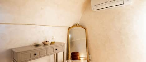 Un baño con tocador, espejo, toallero y unidad de aire acondicionado.