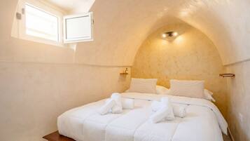 Una camera da letto con soffitto a volta, un letto con lenzuola bianche e una finestra.