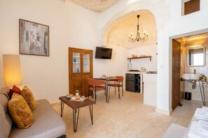 Un soggiorno con divano, un'area pranzo con sedie, una cucina con televisore e un bagno con asciugamani.