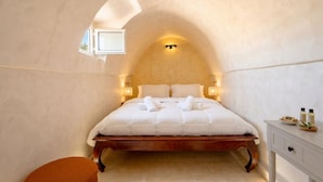 Een slaapkamer met een houten bed, een klein raam en een nachtkastje met toiletartikelen.