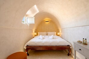 Ein Schlafzimmer mit einem hölzernen Bett, einem kleinen Fenster und einem Nachttisch mit Toilettenartikeln.
