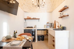 Una cocina compacta con comedor, una araña y estantes empotrados.