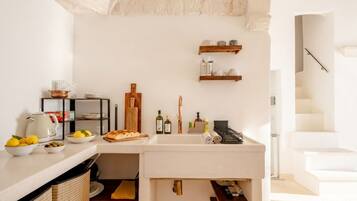 Una cucina con un piano di lavoro bianco, un lavello e una mensola in legno sopra.