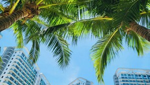 A high-rise hotel with multiple balconies and a clear view of the sky. - Soothing 2-bedrooms lodge with Perfect manmade beach & pool view (Parañaque)