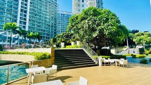 A rooftop pool area with outdoor seating, a staircase, and high-rise buildings in the background. - Soothing 2-bedrooms lodge with Perfect manmade beach & pool view (Parañaque)