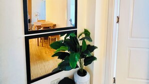 A hallway with a white door, a mirror, a potted plant, and a trash bin. - Soothing 2-bedrooms lodge with Perfect manmade beach & pool view (Parañaque)