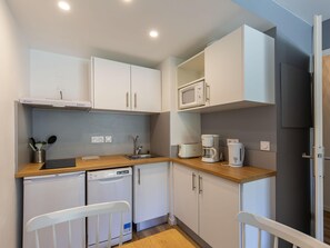 A compact kitchen with white cabinets, a microwave, a coffee maker, and a dishwasher. - Alpine Base in Auris-en-oisans (Germ)