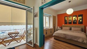 A bedroom with a bed, a balcony with a table and chairs, and a view of the outside. - Cozy Suite in Kolonaki (Athens)