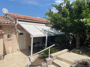 A covered patio with a table and chairs, a white door, and a satellite dish. - Le Paradis de Coti-chivari: Ocean views, scrubland, and eucalyptus forest. (Coti-Chiavari)