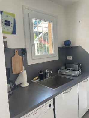 A kitchen with a Bosch dishwasher, a window, a toaster, and a sink.