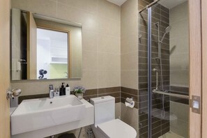 Ein Badezimmer mit Dusche, Waschbecken, Toilette und Spiegel.