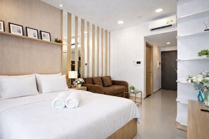 Ein Hotelzimmer mit einem Bett, einem Sofa, einem kleinen Tisch und einem Regal mit Blumen.