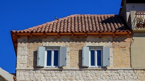 A stone building with three windows, each with shutters, and a tiled roof. - Balturio Boutique House (Kaštel Stari)