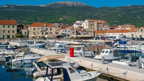 A marina with boats docked, buildings with red roofs, and a mountainous backdrop. - Balturio Boutique House (Kaštel Stari)