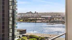 A high-rise building with a view of a waterfront cityscape, including a bridge and industrial buildings. - Marina-view 1-bed Apartment in Docklands (Melbourne)