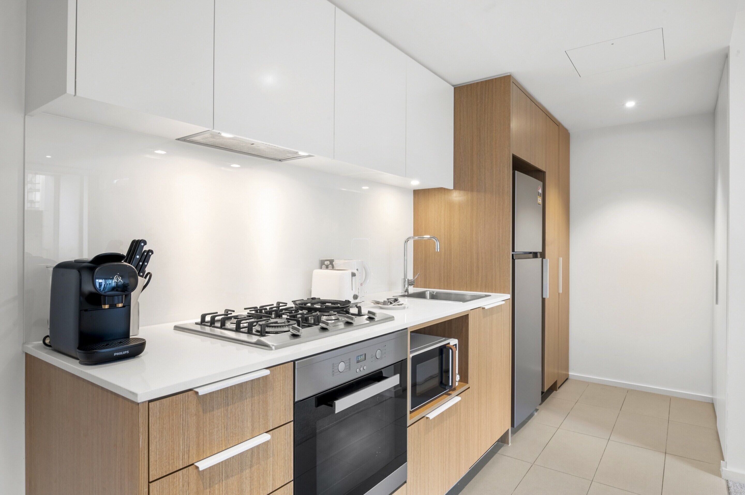 A modern kitchen with a gas stove, coffee maker, microwave, and built-in oven.