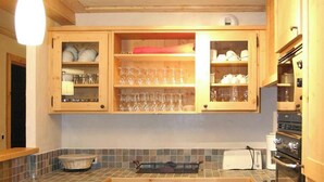 A kitchen with wooden cabinets, a tiled backsplash, a sink, a stove, and overhead lighting. - Alpine Apartment With Beautiful Views (Les Deux Alpes)