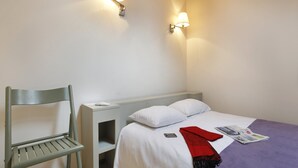 A bedroom with a bed, a chair, a nightstand, and two wall-mounted lights. - Smart Stay With Mezzanine for Four (Merville)