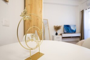 A modern room with a white bed, a gold decorative piece, a wooden panel, a white dresser, a vase, and a painting on the wall. - Don`s Studio by Tok Apartments (Durrës)