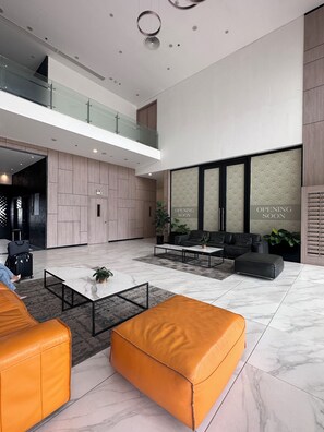 A spacious lobby with a high ceiling, a mezzanine level, and a seating area with sofas and a coffee table. - Muse Hanoi PentStudio West Lake (Hanoi)