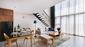 Ein modernes Wohnzimmer mit Essbereich, einer Treppe und großen Fenstern.