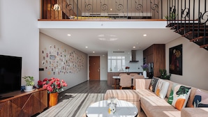 Ein modernes Wohnzimmer mit einer Couch, einem Couchtisch und einem Fernseher. Eine Treppe führt zu einer oberen Ebene.
