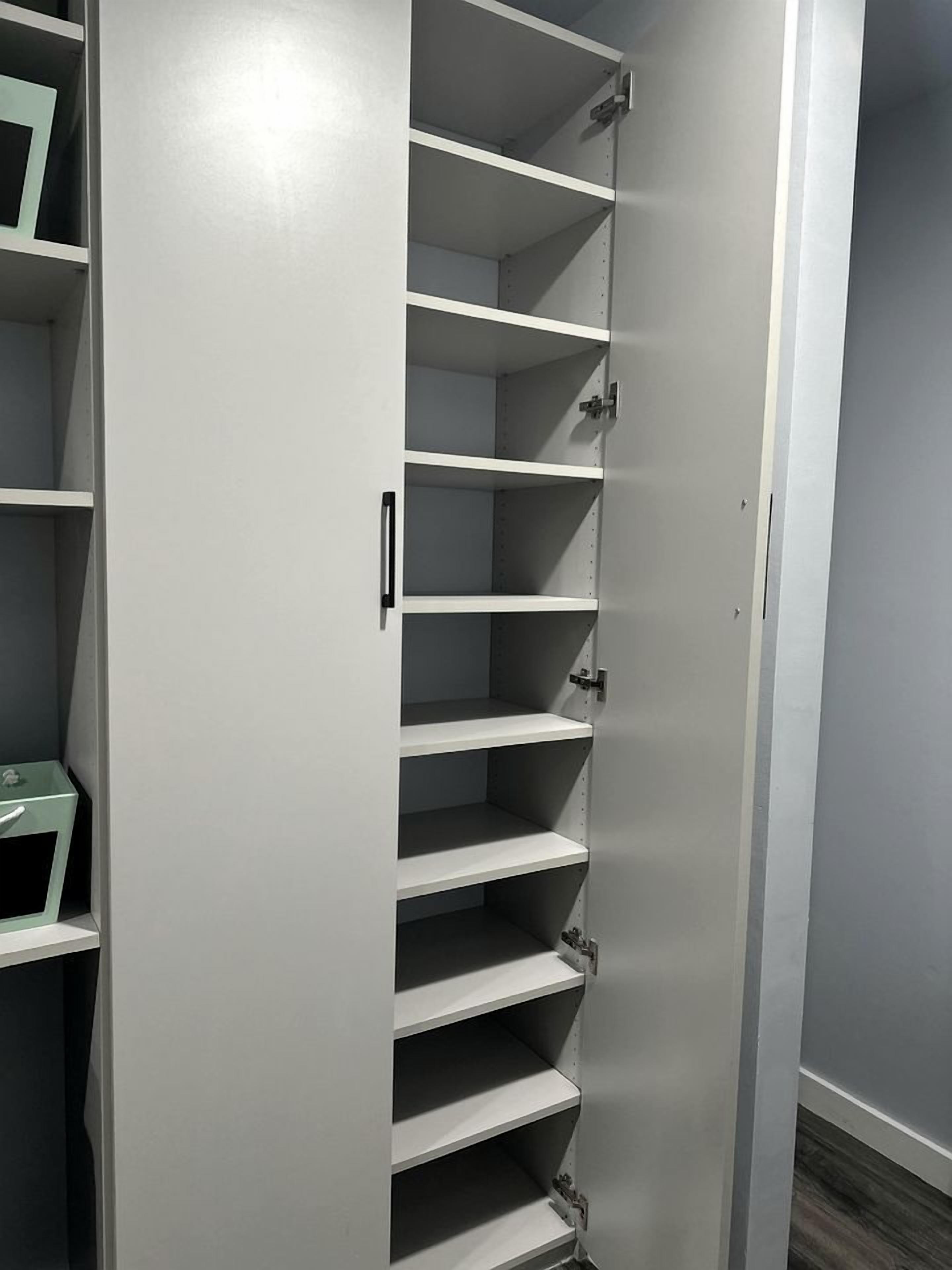 Un placard fermé, de type dressing, avec plusieurs étagères et une poignée.