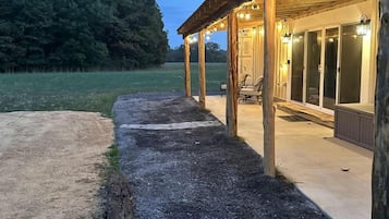 A wooden building with a covered patio area, a gravel path, and a forested background.