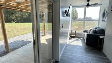 Un intérieur moderne avec une porte-fenêtre coulissante donnant sur un espace extérieur, un ventilateur de plafond et un canapé.