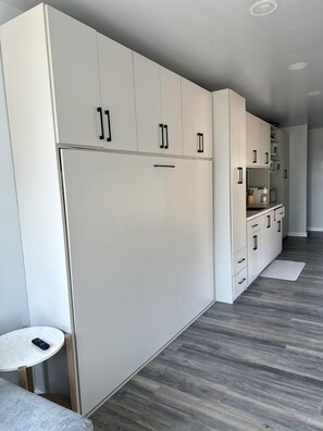 Una cocina moderna con armarios blancos, horno empotrado y una pequeña mesa redonda.