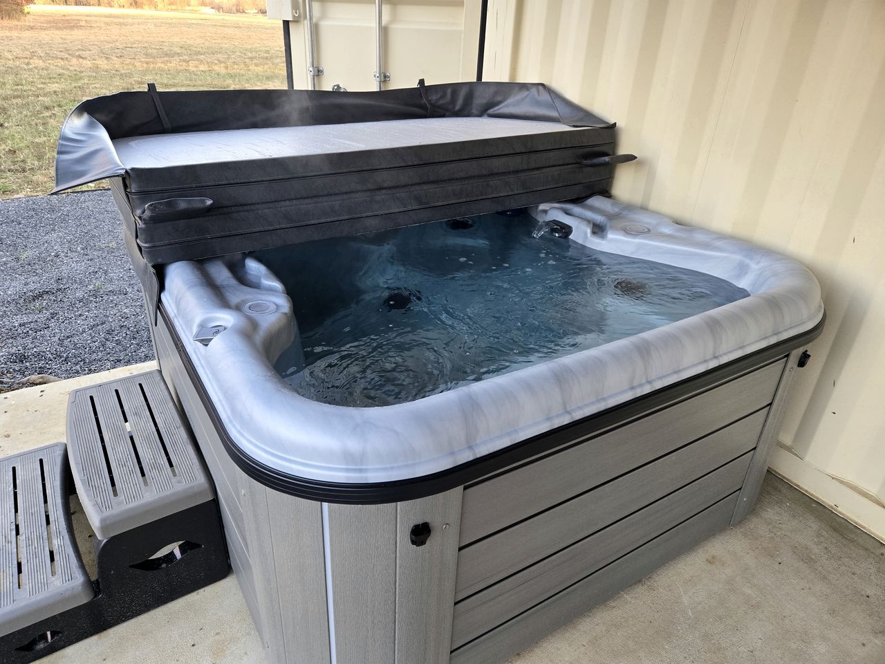 A hot tub with a cover, steps, and a metal frame.