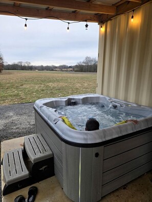 Een hottub voor twee personen, een houten terras en uitzicht over een veld.