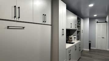 A modern kitchen with grey cabinetry, black handles, and a wooden floor.