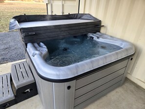 A hot tub with a cover, steps, and a metal frame.
