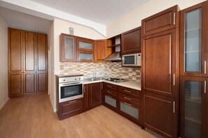 Eine Küche mit Holzschränken, einer Mikrowelle, einem Backofen und einer gefliesten Spritzschutzwand.