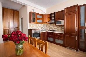 Eine Küche mit Holzausstattung, einer Mikrowelle, einem Backofen und einem Esstisch mit Stühlen.