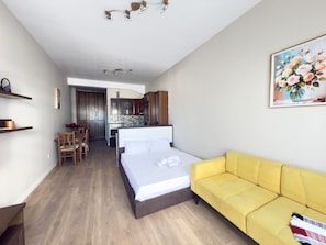 Ein Hotelzimmer mit einem Bett, einem gelben Sofa, einer Essecke und einer Küche.