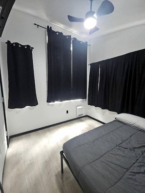 A bedroom with a bed, a ceiling fan, and black curtains. - Peaceful Tiny Cabin Escape With Onsite Play Area Close To River Adventures in Houston, Alaska (Houston)