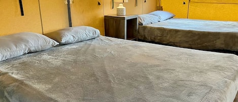 Una stanza con due letti, un comodino e una finestra con tende.