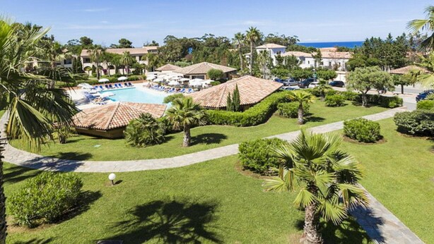 A resort with a swimming pool, palm trees, and a view of the ocean. - Coastal AC Stay Near Bravone for 4 (Linguizzetta)