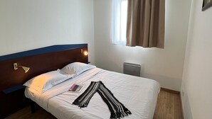 A single bed with white bedding, a striped blanket, a bedside lamp, and a window with curtains. - Modern Family Apartment With Terrace (Bolquere)