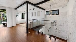 Un intérieur moderne avec un escalier, des murs en briques blanches et un plancher en bois.