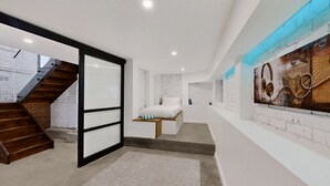 Un intérieur moderne avec un escalier, un lit doté de rangements et un mur orné d’un motif graphique.