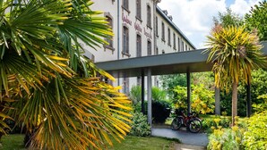 A building with a covered entrance, palm trees, and a bicycle parked outside. - 2-room Dinan Flat for 4 (Dinan)