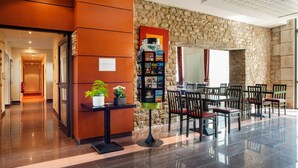 A hotel lobby with a reception desk, a stone wall, a seating area with tables and chairs, and a fire extinguisher. - 2-room Dinan Flat for 4 (Dinan)