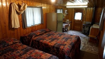 A cabin with two beds, a kitchenette, a dining area, and a fireplace.