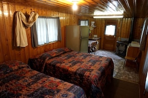 A cabin with two beds, a kitchenette, a dining area, and a fireplace. - Remote and Cozy Mountain Cabin Nestled in the Poudre Canyon, Perfect for a Pet Friendly Glamping Retreat (Bellvue)